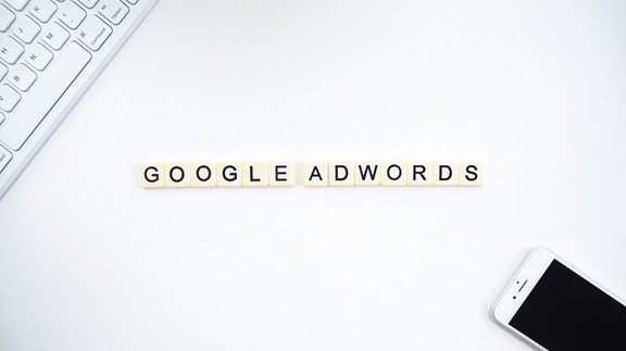 Google AdWords spelled with Scrabble tiles on a white surface.